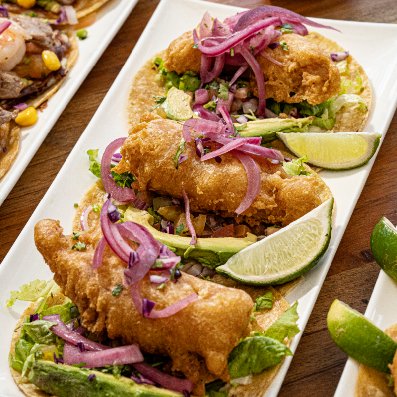 3 tortillas de maíz con filete de pescado empanizado, cama de lechuga, chirmol y aguacate. Aderezado con salsa chipotle.